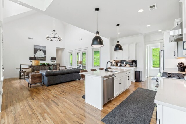 kitchen with dishwasher, a kitchen island with sink, white cabinetry, and light hardwood / wood-style flooring