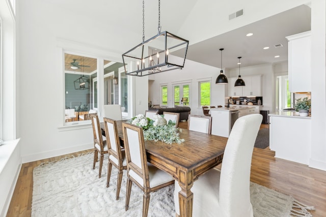 dining space with sink, an inviting chandelier, light hardwood / wood-style flooring, and a high ceiling