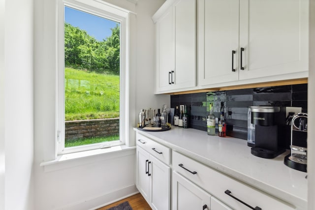 kitchen featuring hardwood / wood-style floors, tasteful backsplash, light stone countertops, and white cabinets