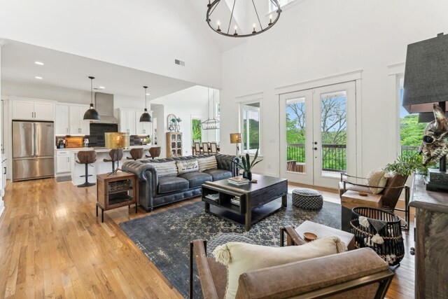 living room featuring a wealth of natural light, light hardwood / wood-style flooring, a chandelier, and french doors