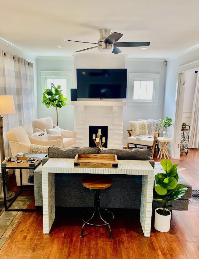 living area featuring a ceiling fan, wood finished floors, a high end fireplace, and ornamental molding