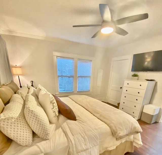 bedroom with a ceiling fan, wood finished floors, and ornamental molding