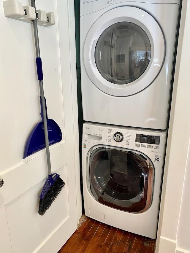 laundry room with laundry area, stacked washer and clothes dryer, and dark wood-style flooring