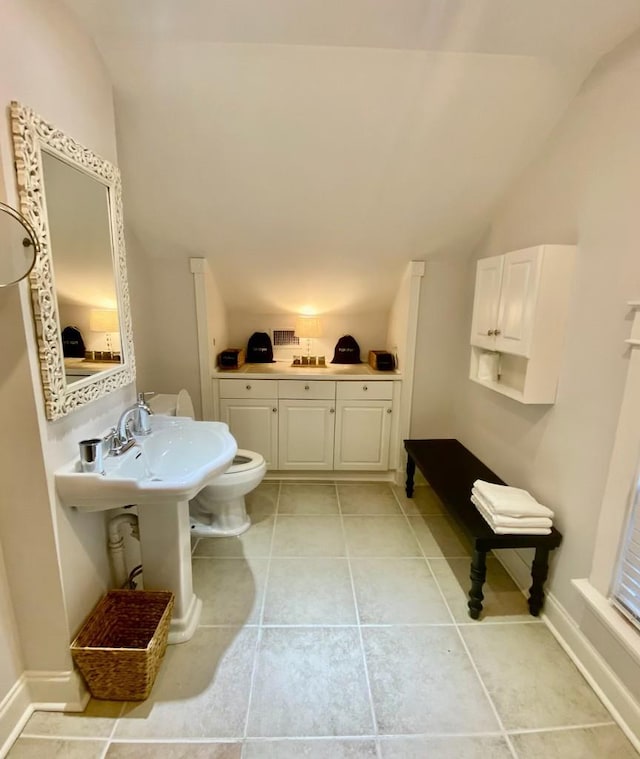 bathroom with baseboards, lofted ceiling, toilet, and tile patterned flooring