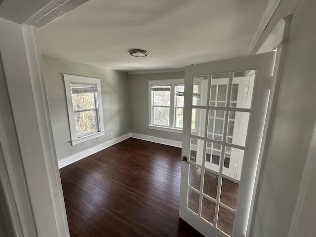 spare room featuring dark wood finished floors, french doors, and baseboards