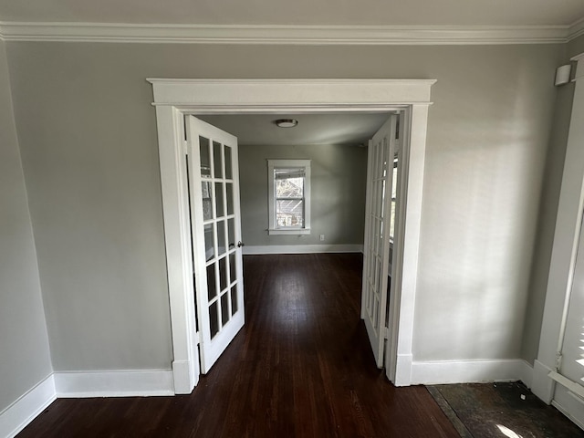 corridor featuring dark wood-type flooring, crown molding, and baseboards