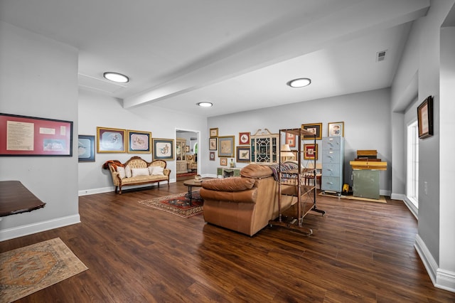 living area with visible vents, baseboards, wood finished floors, and beamed ceiling