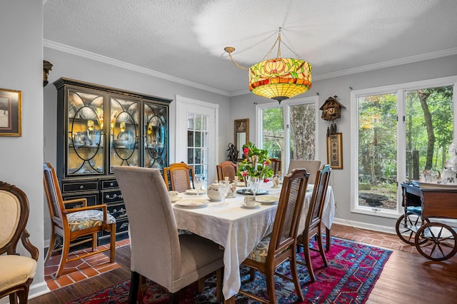 dining room with crown molding, a textured ceiling, baseboards, and wood finished floors