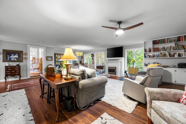 living area featuring a fireplace with flush hearth, ornamental molding, ceiling fan, a textured ceiling, and wood finished floors