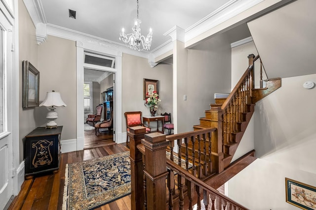 interior space with hardwood / wood-style flooring, ornamental molding, a chandelier, baseboards, and stairs