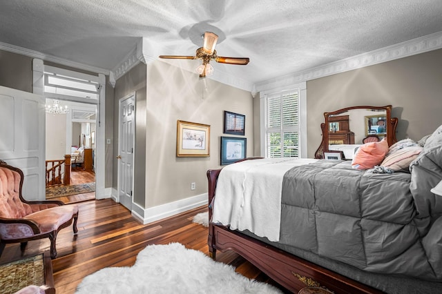 bedroom featuring a textured ceiling, ceiling fan with notable chandelier, dark wood-style flooring, baseboards, and ornamental molding