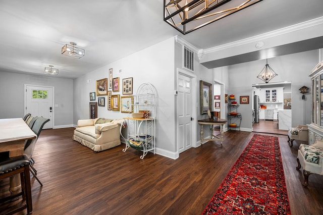 living area featuring a notable chandelier, baseboards, visible vents, and wood finished floors