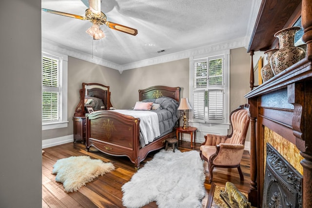 bedroom with baseboards, visible vents, wood finished floors, a textured ceiling, and a fireplace