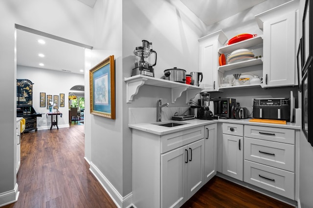 kitchen with arched walkways, light countertops, a sink, and open shelves