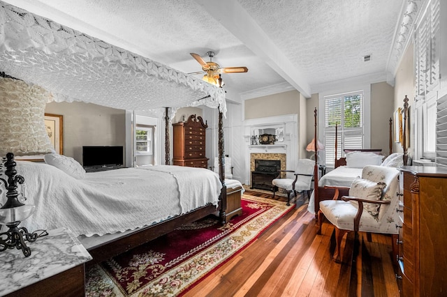 bedroom featuring visible vents, a fireplace, a textured ceiling, and hardwood / wood-style flooring