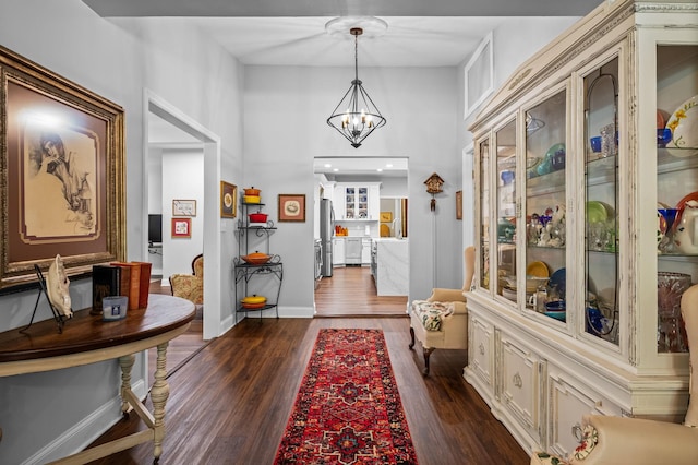 foyer entrance with baseboards, a chandelier, and dark wood-type flooring