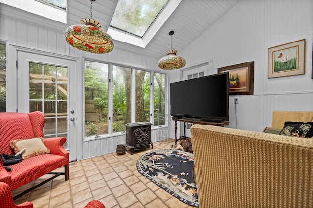 living room featuring a wood stove and vaulted ceiling with skylight