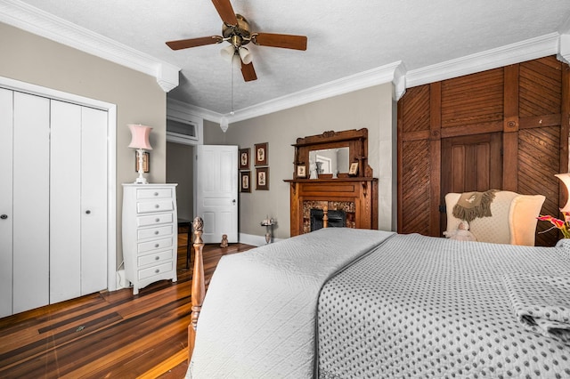 bedroom featuring a ceiling fan, dark wood-style flooring, a textured ceiling, crown molding, and a fireplace