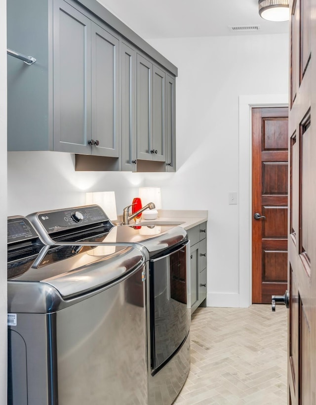 clothes washing area featuring cabinet space, independent washer and dryer, visible vents, and a sink