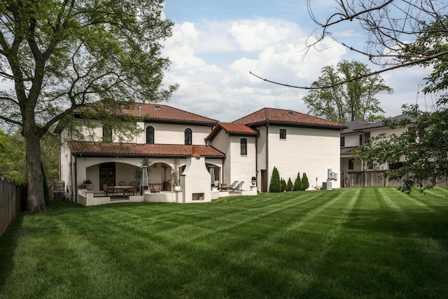 back of property featuring a patio, a yard, a fenced backyard, and a tiled roof