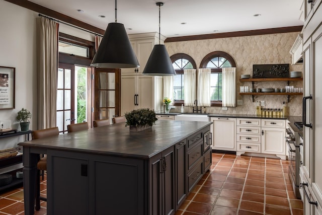 kitchen featuring dark tile patterned flooring, dark countertops, a kitchen island, appliances with stainless steel finishes, and a sink