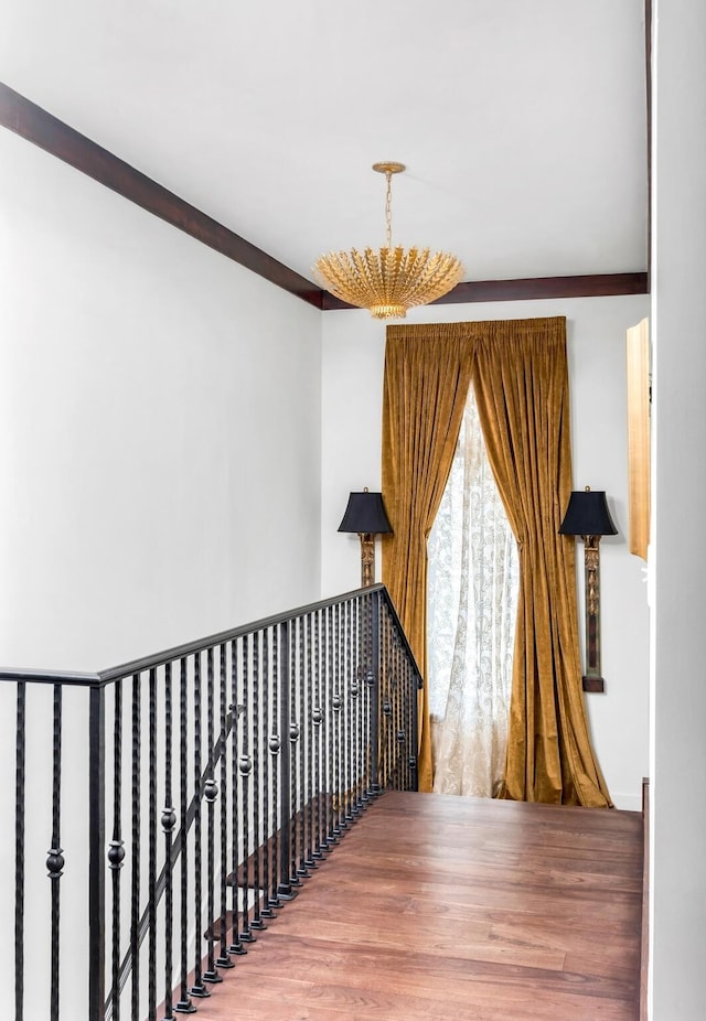 corridor featuring a notable chandelier, wood finished floors, and an upstairs landing