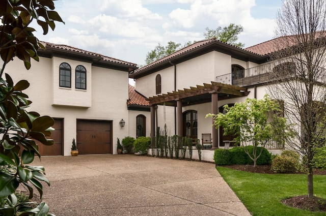 mediterranean / spanish house with an attached garage, concrete driveway, a tiled roof, stucco siding, and a front lawn