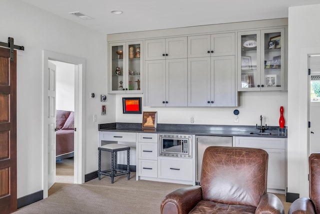 bar with a barn door, light carpet, a sink, visible vents, and stainless steel microwave