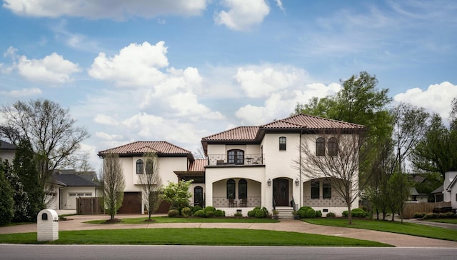 mediterranean / spanish-style house with a porch, a front yard, a tile roof, and a balcony