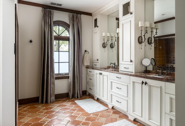 full bathroom with a stall shower, a sink, visible vents, and baseboards