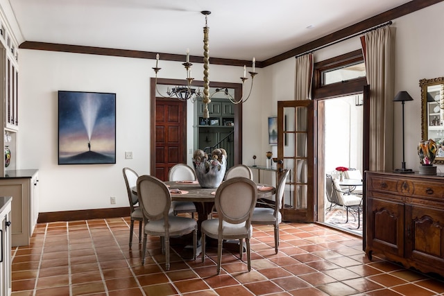 dining space featuring ornamental molding, a notable chandelier, dark tile patterned floors, and baseboards