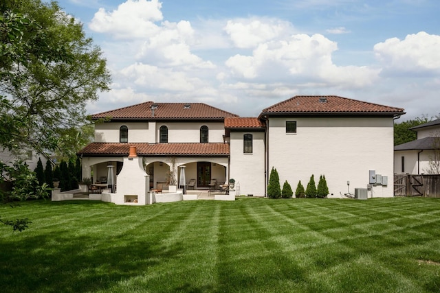 back of property with a tile roof, fence, cooling unit, a yard, and a patio area