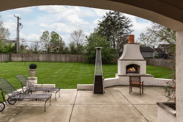 view of patio / terrace with a fenced backyard and a lit fireplace