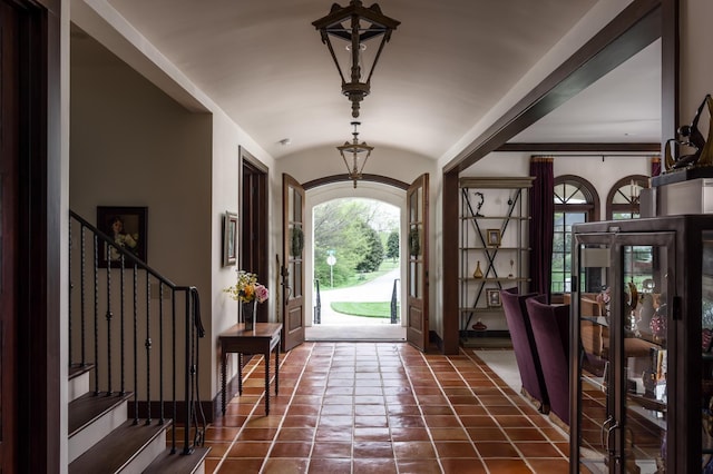 foyer with stairs, vaulted ceiling, arched walkways, and baseboards