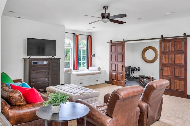 living room featuring a ceiling fan, carpet flooring, and a barn door