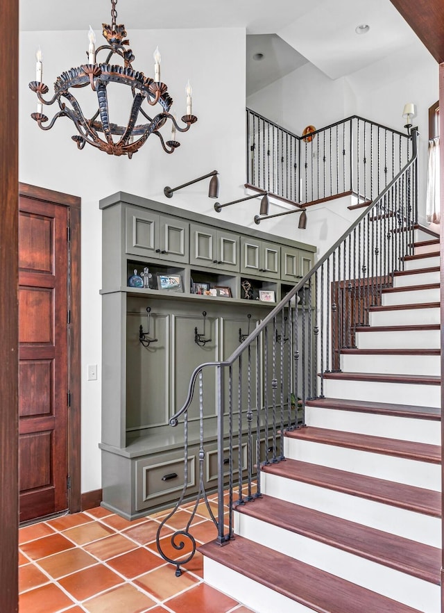 stairs featuring a towering ceiling, baseboards, a chandelier, and tile patterned floors