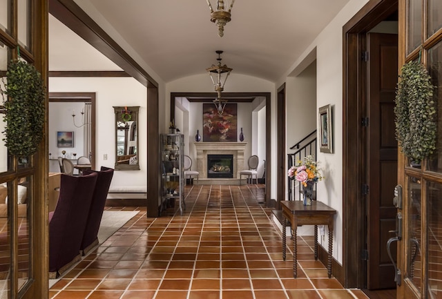 hallway with lofted ceiling, dark tile patterned floors, and stairway