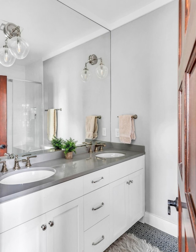 full bathroom featuring baseboards, double vanity, a sink, and a shower stall