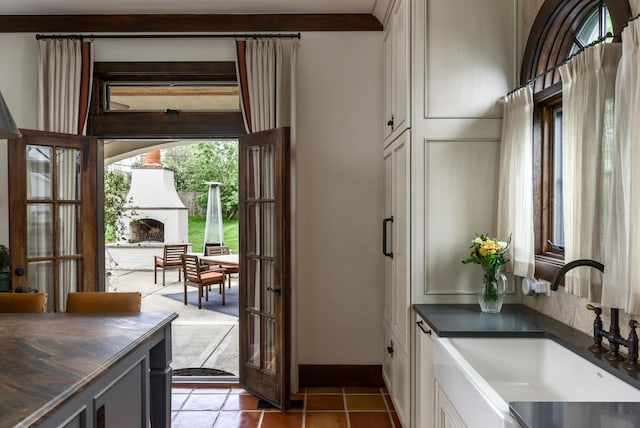 entryway featuring light tile patterned floors, french doors, a sink, and baseboards