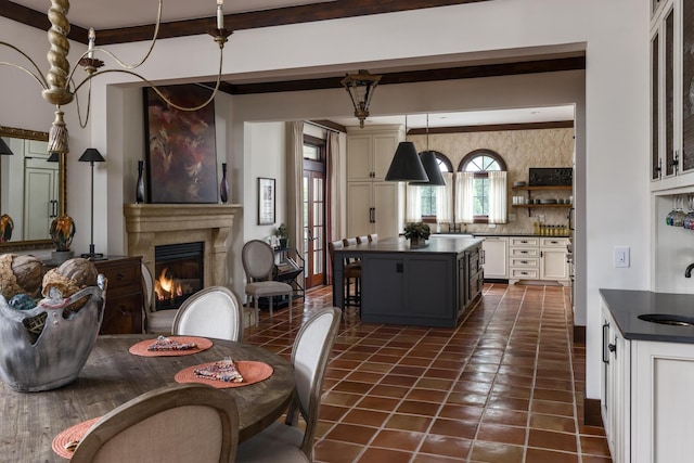 kitchen featuring dark countertops, a center island, dark tile patterned flooring, and a glass covered fireplace