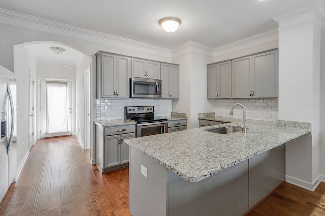 kitchen featuring appliances with stainless steel finishes, light stone counters, hardwood / wood-style floors, and sink