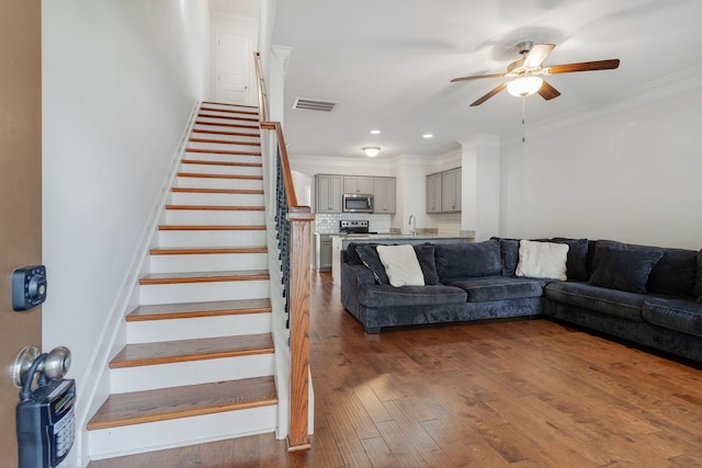 living room featuring ceiling fan, crown molding, wood-type flooring, and sink