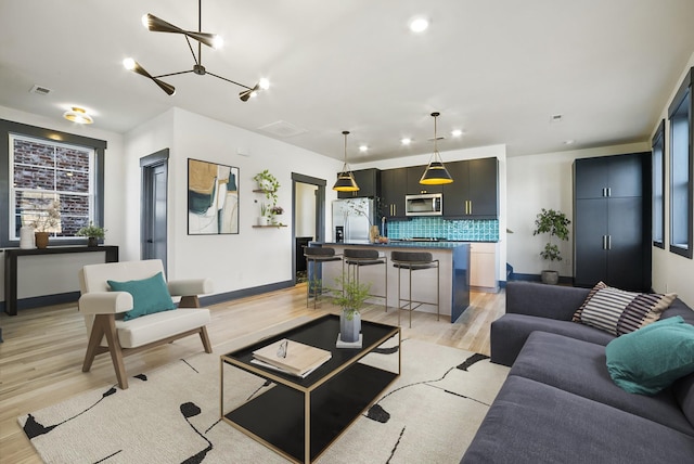 living room with light wood-type flooring and a notable chandelier