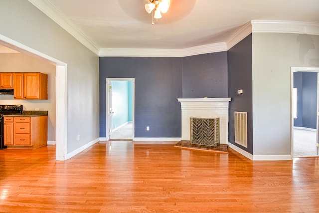 unfurnished living room featuring ceiling fan, ornamental molding, and light wood-type flooring