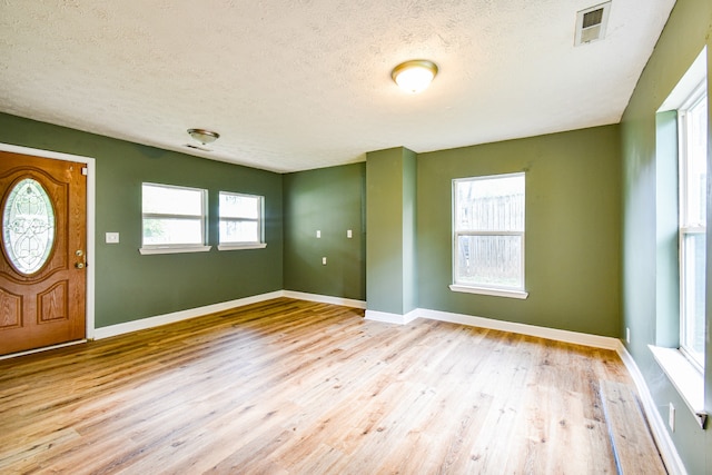 foyer entrance with a textured ceiling and light hardwood / wood-style floors