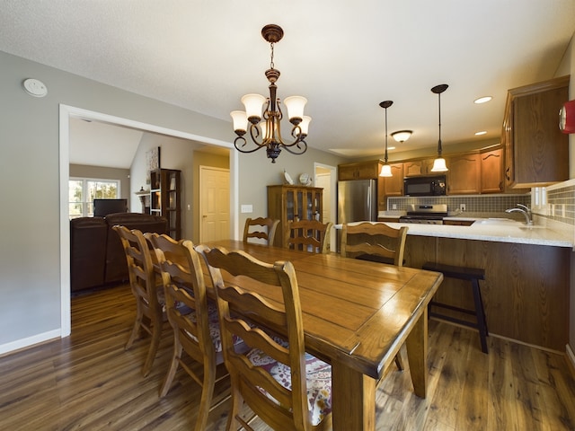 dining space with sink, lofted ceiling, a chandelier, and dark hardwood / wood-style flooring