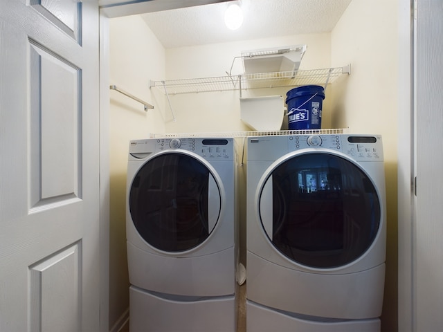 washroom featuring washing machine and clothes dryer and a textured ceiling