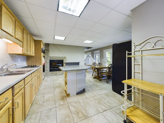 kitchen with backsplash, a paneled ceiling, brick wall, and a fireplace