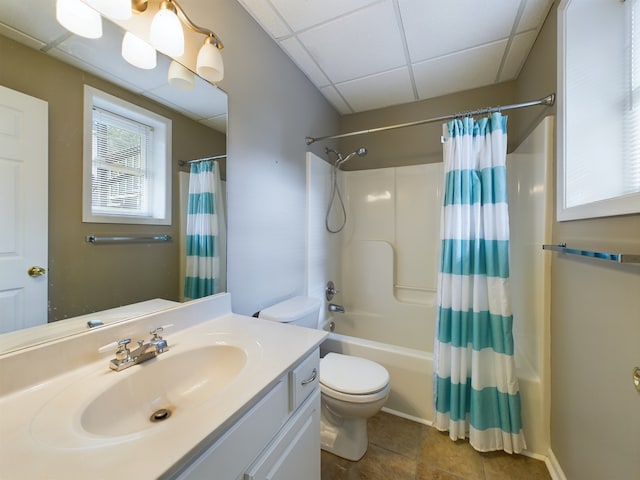 full bathroom with a drop ceiling, shower / bath combo with shower curtain, tile patterned flooring, vanity, and toilet