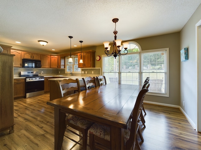 dining space featuring sink, a notable chandelier, a textured ceiling, and dark hardwood / wood-style floors